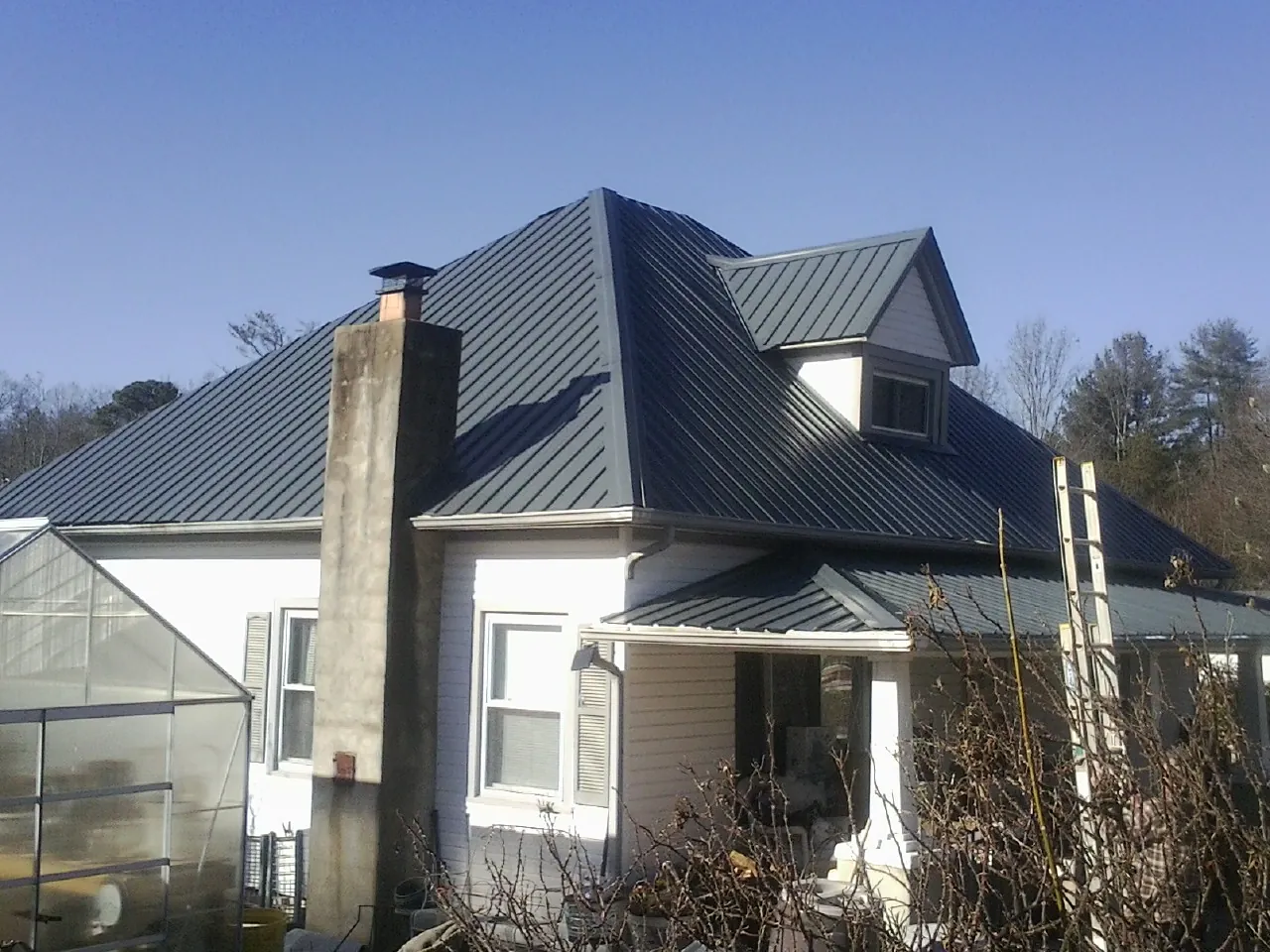 Dark blue standing seam metal roof on a white farmhouse with dormer — Slate & Tile Roof Repair by Roofing Brothers in Half Moon Bay