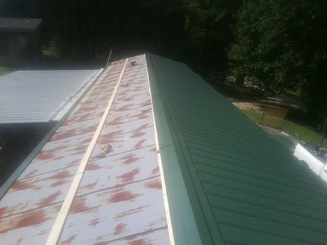Old rusted panels beside newly installed green metal roofing — Wind Damage Roof Repair by Roofing Brothers in Half Moon Bay