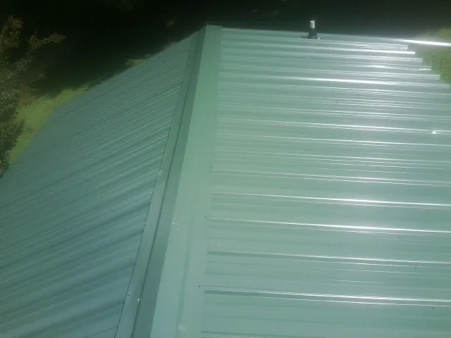 New green metal panels meeting at the ridge of a roof — Flat Roof Repair work by our crew in Half Moon Bay