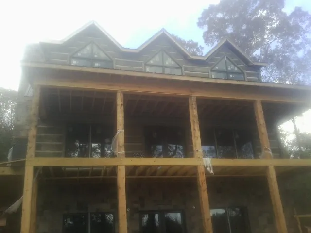 Dormers and porch framing on a large log home under construction — Roof Coating work by our crew in Half Moon Bay