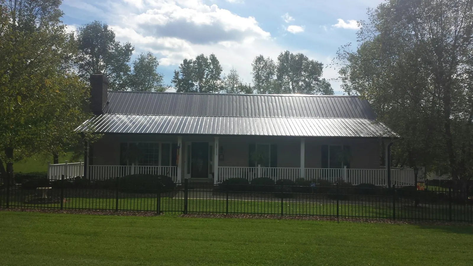 Gray metal roof on a brick ranch with a full width front porch — Gutter Guard Installation work by our crew in Half Moon Bay