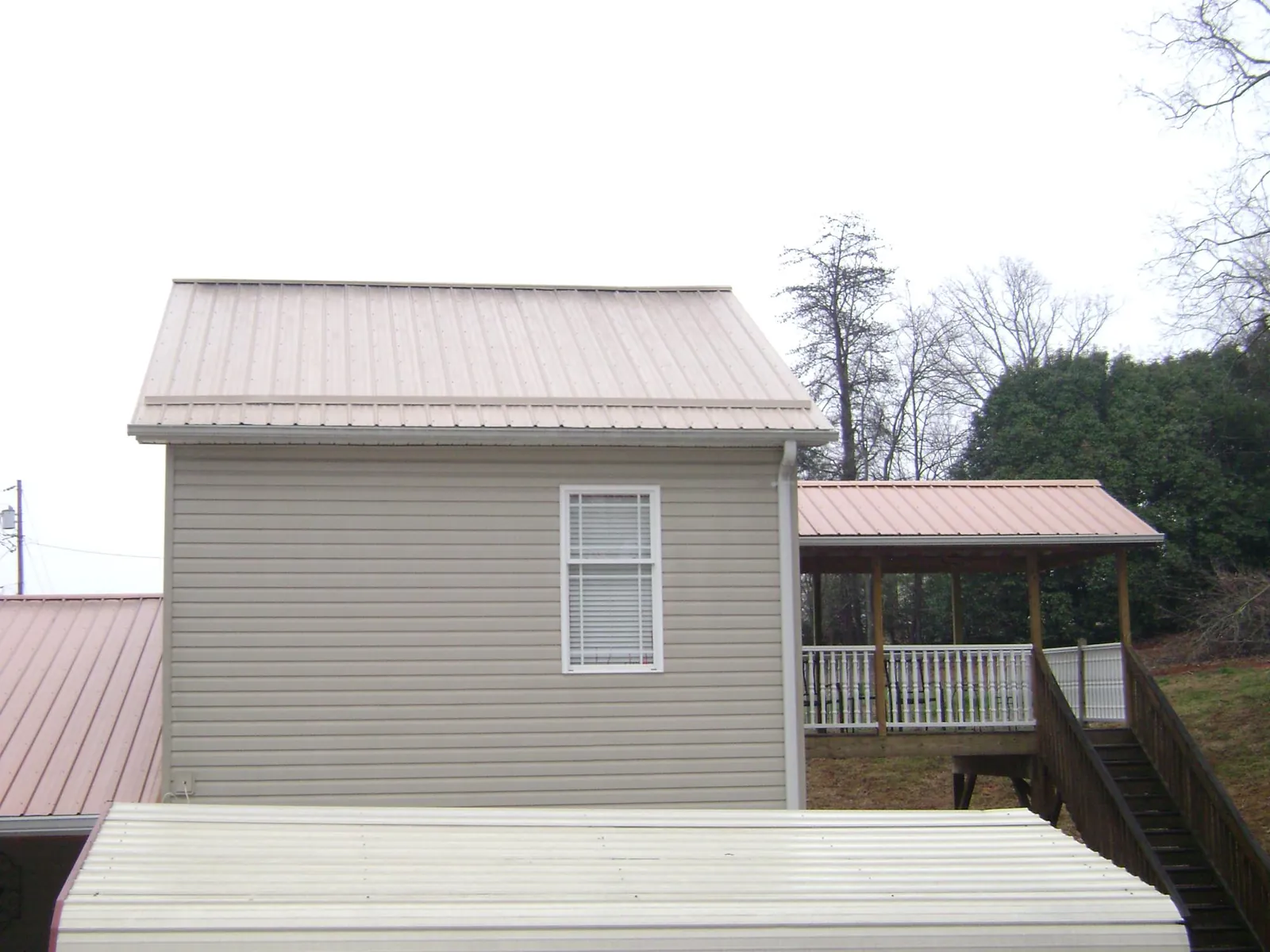 Tan metal roofs on a two story addition and attached porch, from a Roof Replacement job in Half Moon Bay